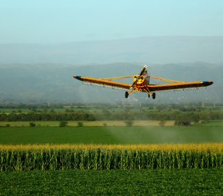 aviao-voando-sobre-o-campo-contra-o-ceu-scaled
